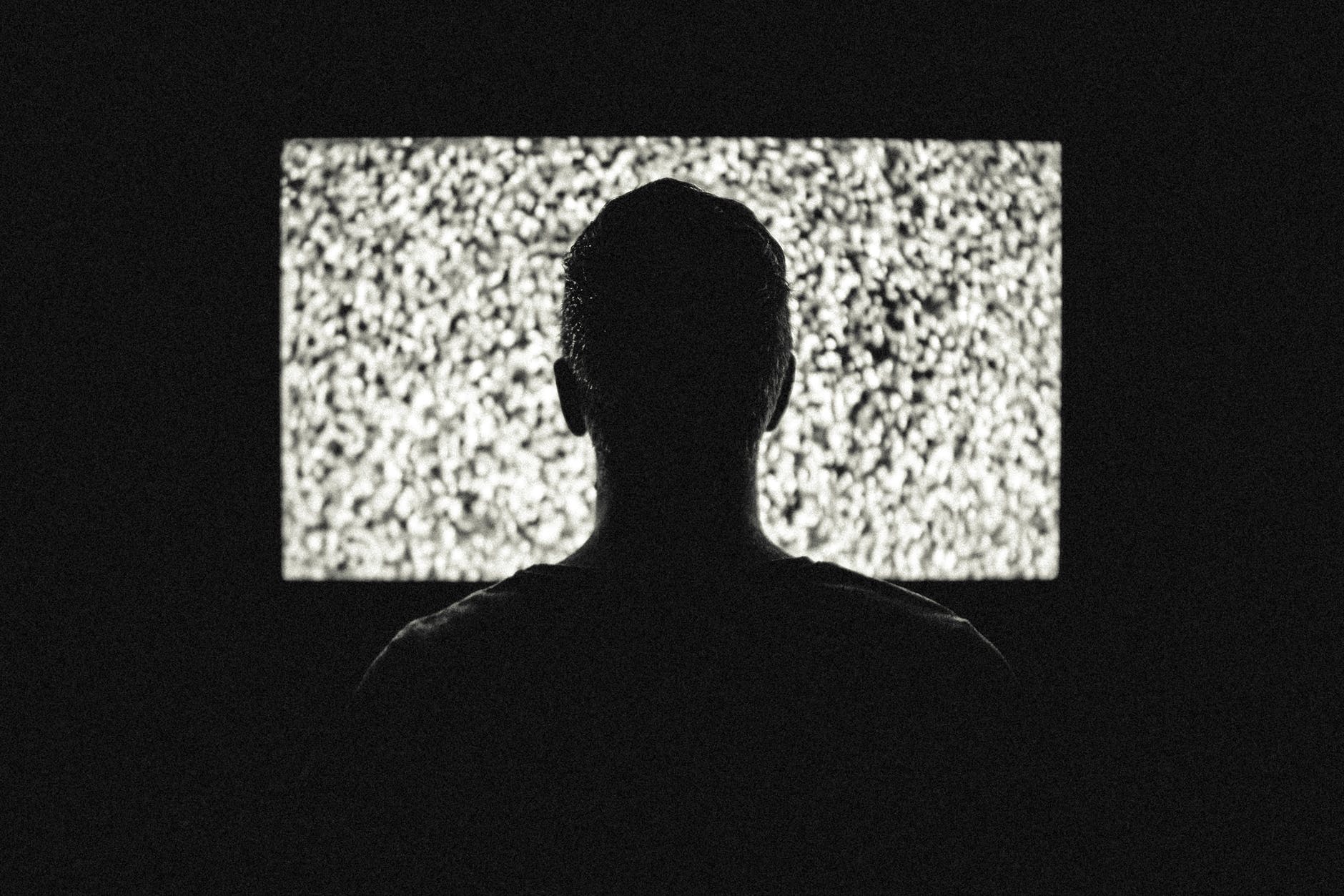 Man sitting in front of static on TV silhouette